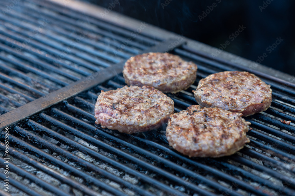 Chef making burger meat at the open air restaurant grill. Festival food, fast food restaurant , cooking meatballs on the grill with tongs in hand Chef making burger meat at the open air restaurant grill. Festival food, fast food restaurant , cooking meatballs on the grill with tongs in hand
