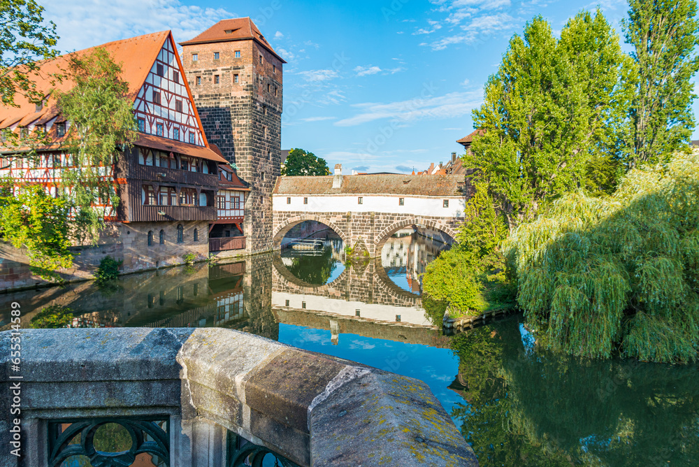 Traditional medieval buildings in the historical centre of Nuremberg, Bavaria, Germany, reflecting in the calm water as a mirror. Stone balcony in the foreground.