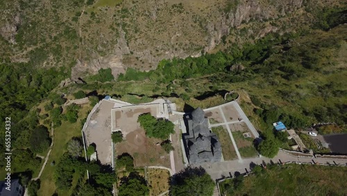 Drone footage reveals the ancient Tegher Monastery in Armenia, perched on a mountain, showcasing its historic beauty and the captivating surrounding landscape photo