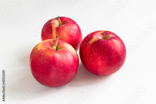 Three red apples on a light background