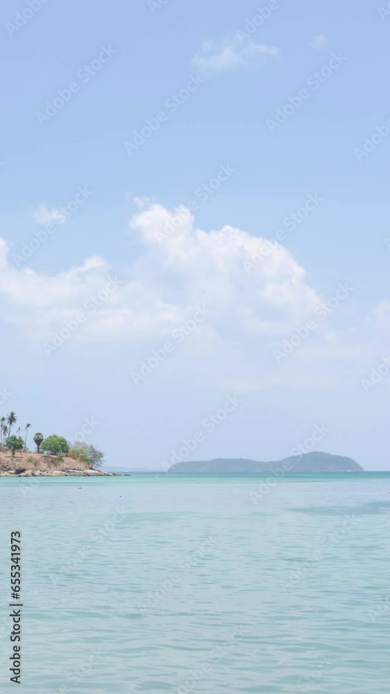 vertical timelapse natural tropical sea under clear sunny blue sky with green island among turquoise sea in summer holiday vacation time. vertical timelapse natural tropical sea under clear sunny blue sky with green island among turquoise sea in summer holiday vacation time.