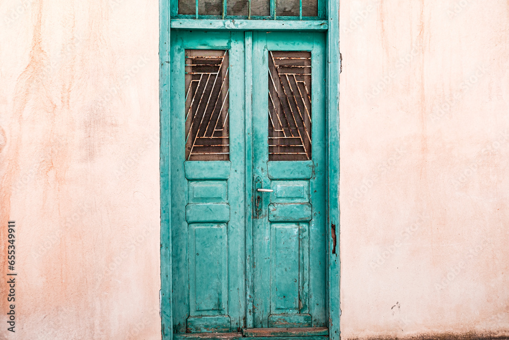 old wooden blue green painted greek door with key in the lock, whitewashed building, traditional steet in Greek islands, cyclades