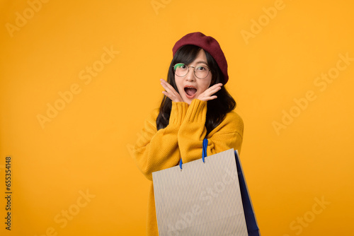 A fashion savvy individual, sporting a red beret and yellow sweater, exults in a shopping spree against a vibrant yellow background.