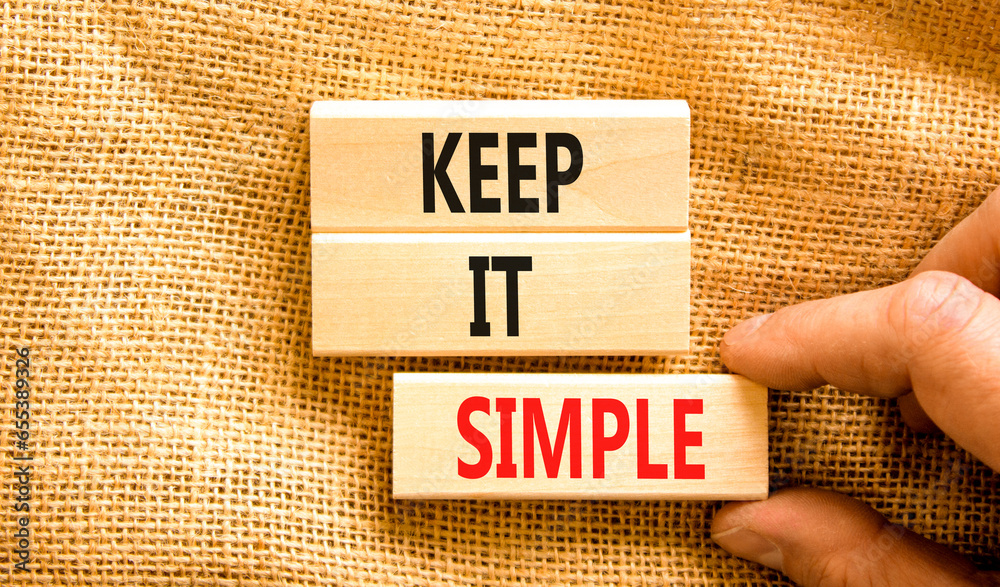 Fototapeta premium Keep it simple symbol. Concept word Keep it simple on beautiful wooden block. Businessman hand. Beautiful canvas table canvas background. Business motivational keep it simple concept. Copy space.