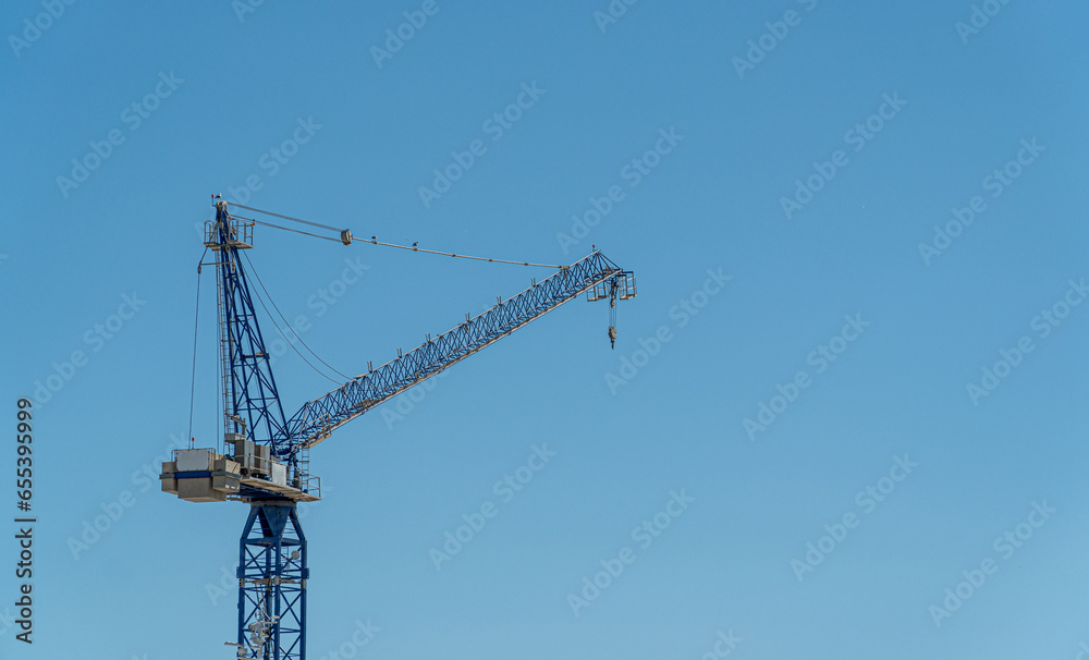 Metal crane for constructing buildings, isolated on blue sky. 