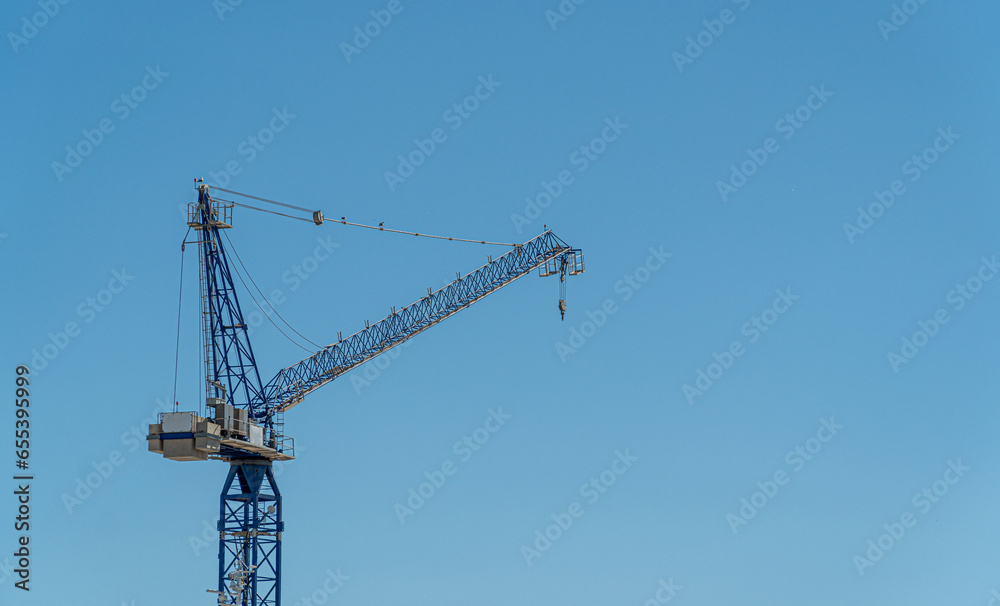 Metal crane for constructing buildings, isolated on blue sky. Metal crane for constructing buildings, isolated on blue sky.