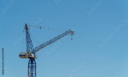 Metal crane for constructing buildings, isolated on blue sky. 