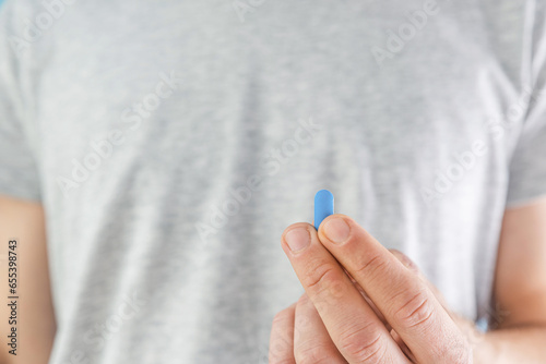 Man holding HIV prevention blue pill in a hand. Pre-Exposure Prophylaxis medicine. Men health. AIDS prevention concept