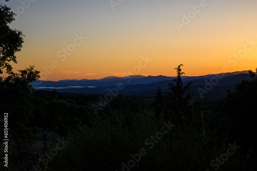 dark sunset with illuminated mountains in the background and dark orange twilight sky
