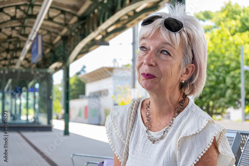 elderly woman 60-65 years old at a bus stop waiting for a train or train photo