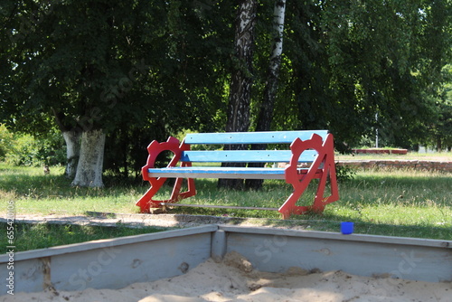 A park bench in the green recreation area. A place to relax near trees, bushes