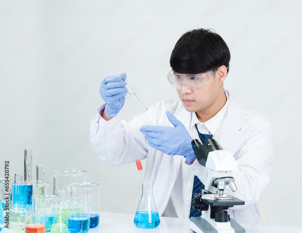 Fototapeta premium Portrait asian man student scientist Wearing a doctor gown in the lab looking hand at chemist. caused by mixing reagents in scientific research laboratories with test tubes and microscope on the table