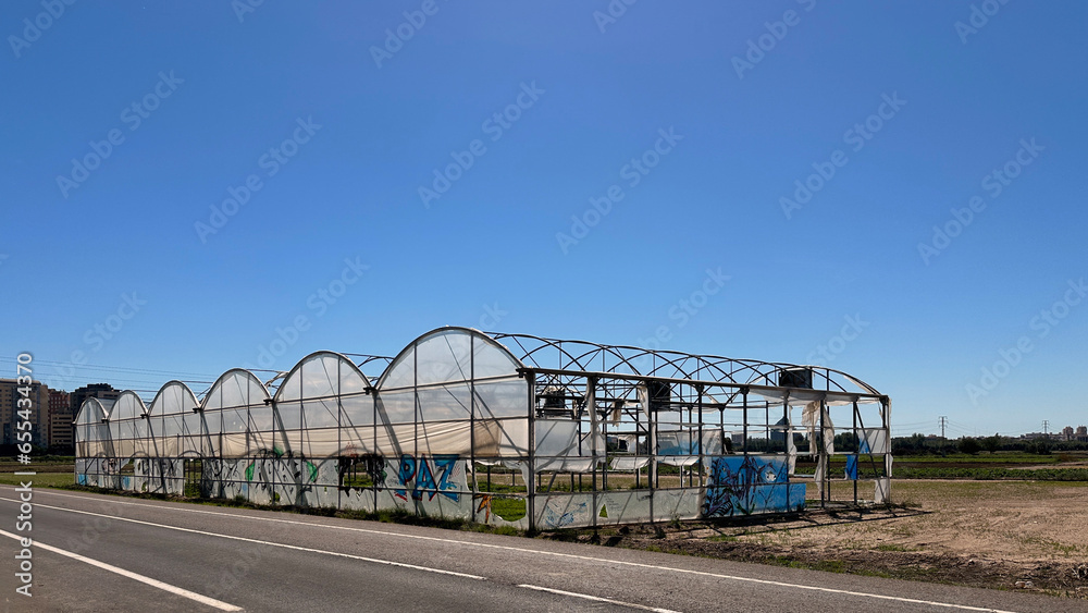 Abandoned greenhouse in the sun with broken plastics Abandoned greenhouse in the sun with broken plastics