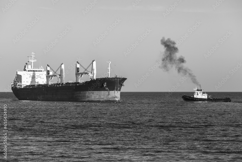Fototapeta premium Bulk carrier and tug boat sail the Black Sea. Varna harbor