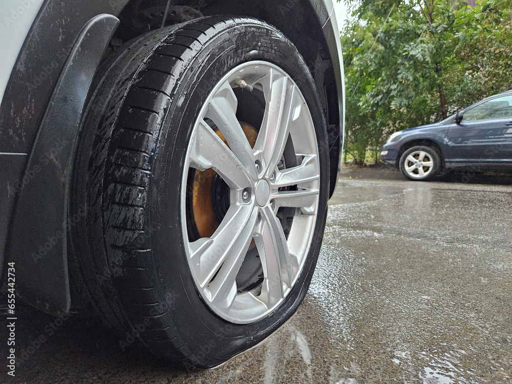 On a wet asphalt road, one of the tires is completely flat 