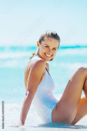 Smiling young woman sitting at seaside © Alliance