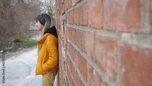 Teen listen music by brick wall. A view of young girl listening the music becasue of her life problems during childhood. photo