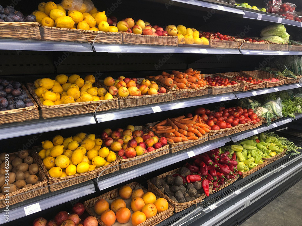 Various fresh vegetables and fruits on shelves in supermarket