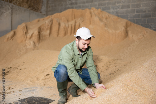 Male farmer holding a handful of soybean husks in an animal feed warehouse