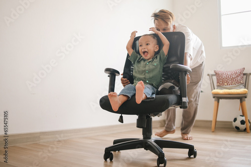 Canvas Print Happy father and son playing with swivel chair at home
