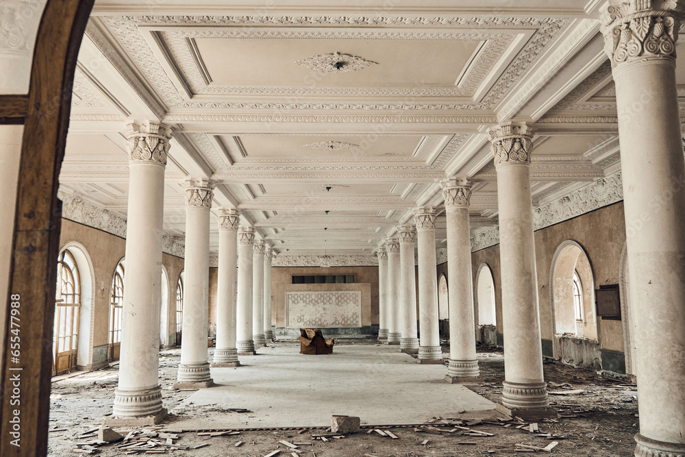 Abandoned soviet spa resort (sanatorium) Shakhter (Miner), in Tskaltubo, Georgia. View of the empty big hall with columns, an old chair in the center. 
 - obrazy, fototapety, plakaty 