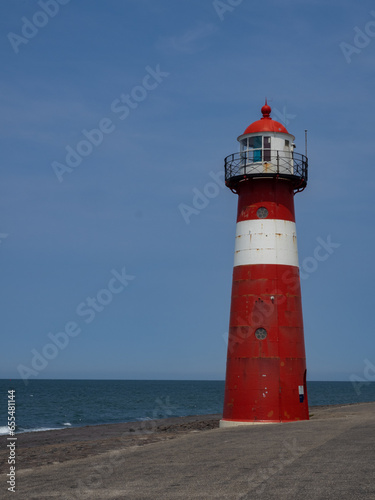 Westkapelle lighthouse, in the Netherlands. Red lighthouse with white stripe. Blue sky in the background.