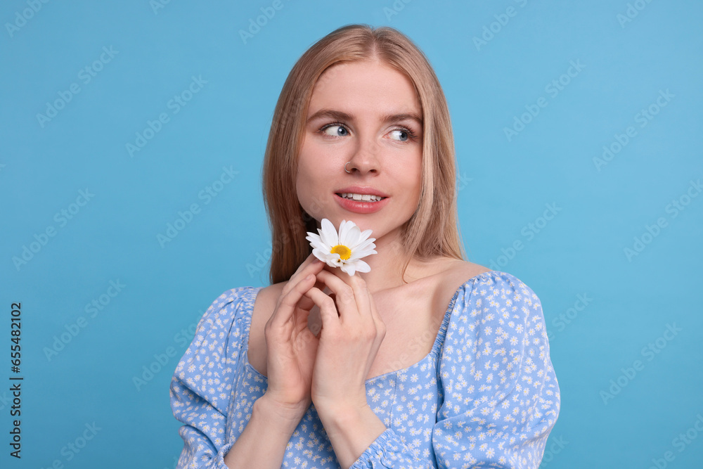 Beautiful woman with spring flower in hands on light blue background Beautiful woman with spring flower in hands on light blue background