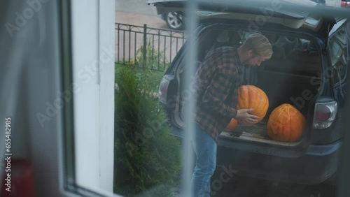 view from the window, a man unloads pumpkins from a car