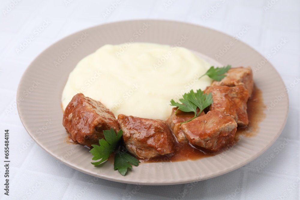 Delicious goulash with mashed potato on white tiled table, closeup