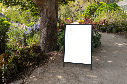 Foto Blank white mockup background template of a standing board placed outdoor on a gravel footpath surrounded by beautiful garden plants