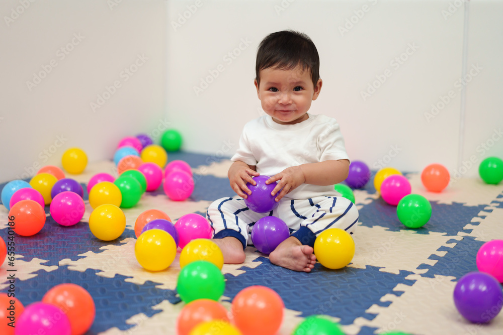 happy infant baby playing colorful balls in playpen happy infant baby playing colorful balls in playpen