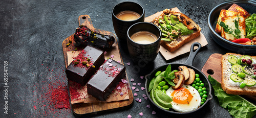 Tasty food with avocado toast, vegetables, eggs on dark background. Helthy breakfast concept