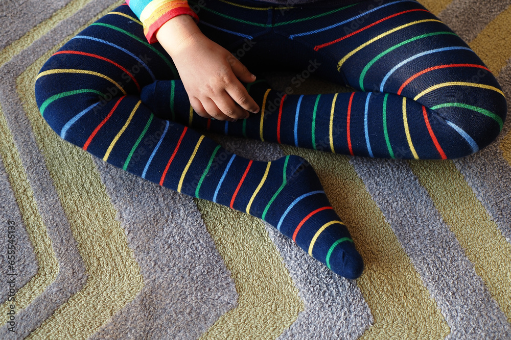 top view of child with Colorful striped socks sitting on carpet top view of child with Colorful striped socks sitting on carpet