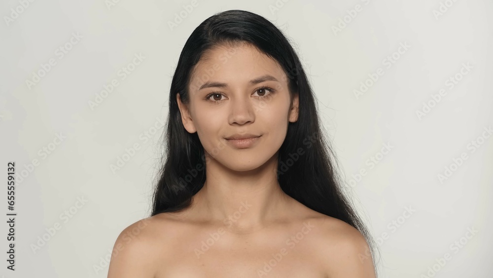 Obraz premium Closeup studio shot of attractive young model. Beautiful asian girl with natural makeup and long hair posing looking at the camera.