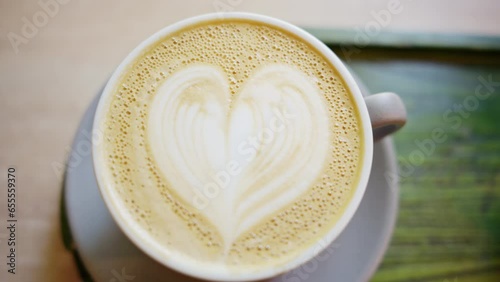 Close vertical view of a coffee foam with painted heart on it photo