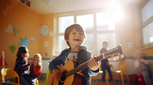 Cheerful cute boy playing guitar in kindergarten classroom