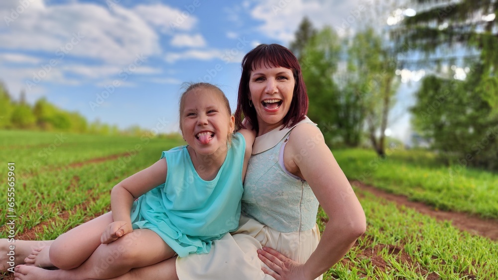 Happy mother and daughter enjoying rest, playing and fun on nature in green field. Woman and girl resting outdoors in summer and spring day Happy mother and daughter enjoying rest, playing and fun on nature in green field. Woman and girl resting outdoors in summer and spring day