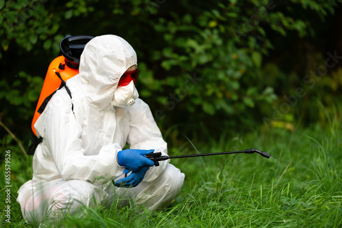 A worker sprays pesticides in an open park on the lawn. Pest control