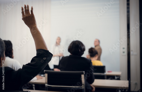 Back view of businesswoman giving hand raise to asking in conference room photo