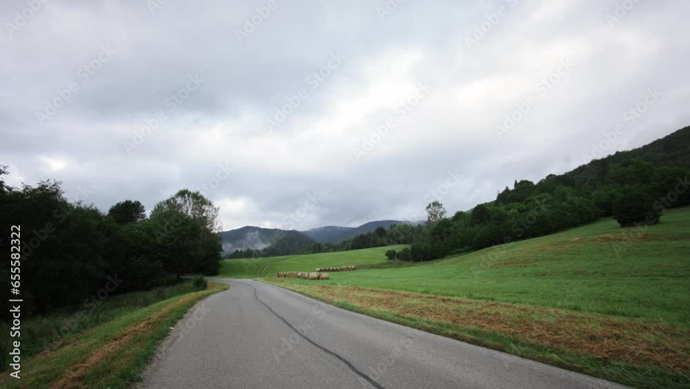 Empty country road with black asphalt line with grassy hillside and foggy mountains in distance Empty country road with black asphalt line with grassy hillside and foggy mountains in distance