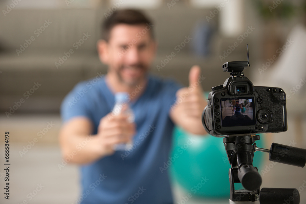 man filming himself holding water bottle after exercising