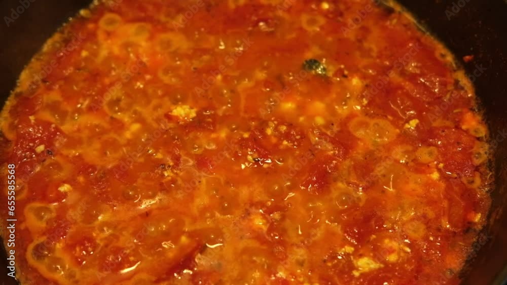 Preparation of Tomato sauce boiling in a pan on the kitchen. Classic home Hot tomato sauce cooking for pizza or pasta. Italian cuisine, food and drink footage. Homemade Sauteed Cooked Chopped Tomatoes Preparation of Tomato sauce boiling in a pan on the kitchen. Classic home Hot tomato sauce cooking for pizza or pasta. Italian cuisine, food and drink footage. Homemade Sauteed Cooked Chopped Tomatoes