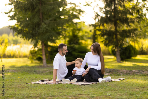 Fototapeta Naklejka Na Ścianę i Meble -  family, leisure and people concept. happy mother, father and little son having picnic at summer park