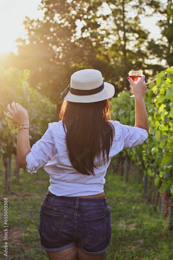 Young beautiful Smiling  italian woman walking at wineyard with a Glass of Red wine.Wine tourism at Tuscany,Italy
