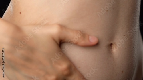 Closeup studio shot of caucasian woman beautiful body part  touching tummy area smooth skin with hand.