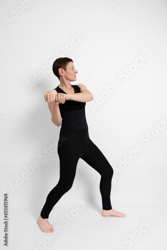 Paris, France - 09 30 2023: Athletic mature woman dressed in black, miming the sporty gesture of baseball. photo