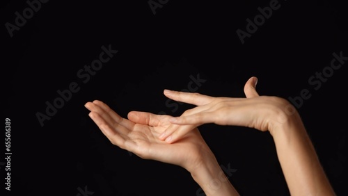 Closeup studio shot of beautiful caucasian woman showing open palm and touching it with finger, isolated on black background.