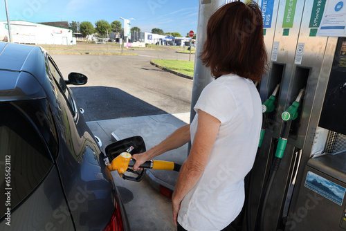 Une femme se sert du carburant dans une pompe à essence photo