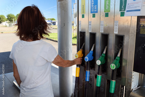 Une femme se sert du carburant dans une pompe à essence photo