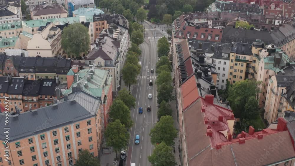 Drone footage of apartment buildings, rooftops and road with traffic at Karlavägen, Stockholm, Sweden during mid-day cloudy weather. Aerial shot orbiting street,  infrastructure in Sverige.